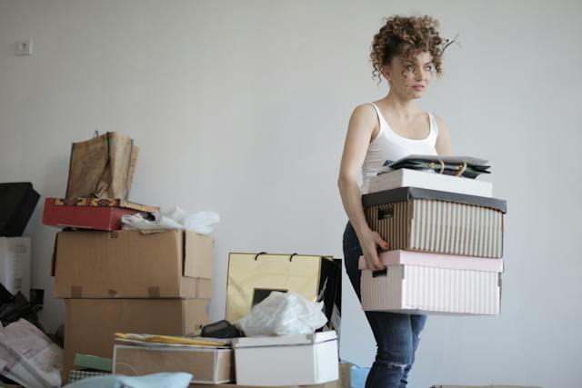 A woman carrying boxes and decluttering before a move.
