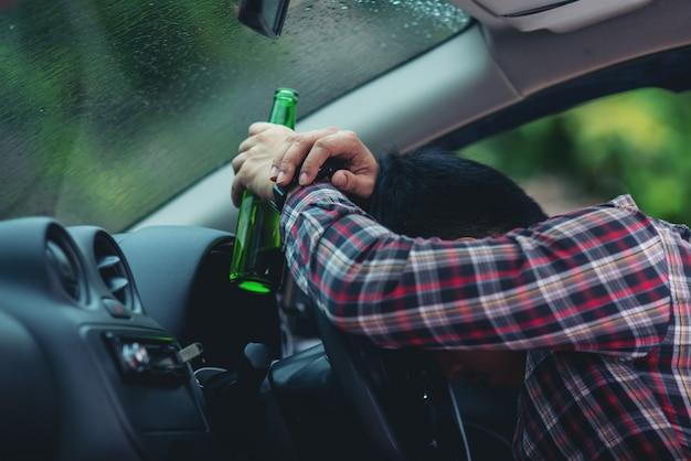 asian man holds a beer bottle while is driving a car