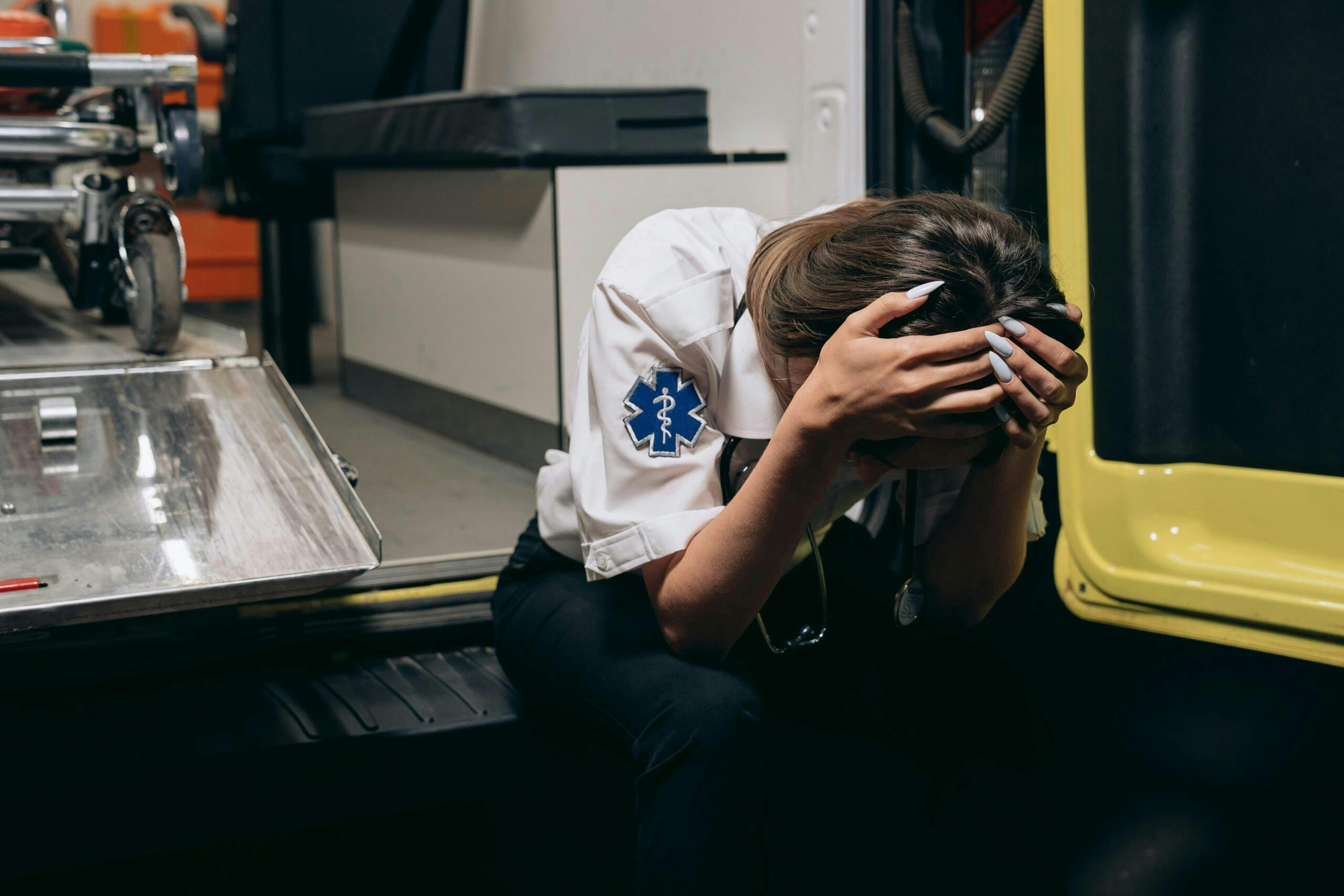 https://www.pexels.com/photo/distraught-paramedic-sitting-with-her-head-in-hands-on-the-bumper-of-an-ambulance-28123720/